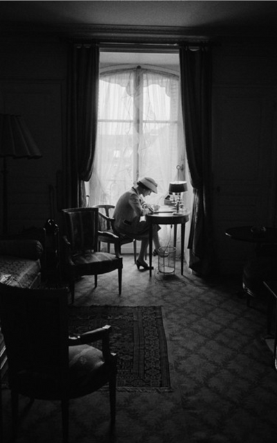 'Coco Chanel writes at Desk in Window, Head Down, 1957' © Mark Shaw